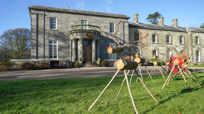 Reindeers made from wood on the lawn in front of a big house